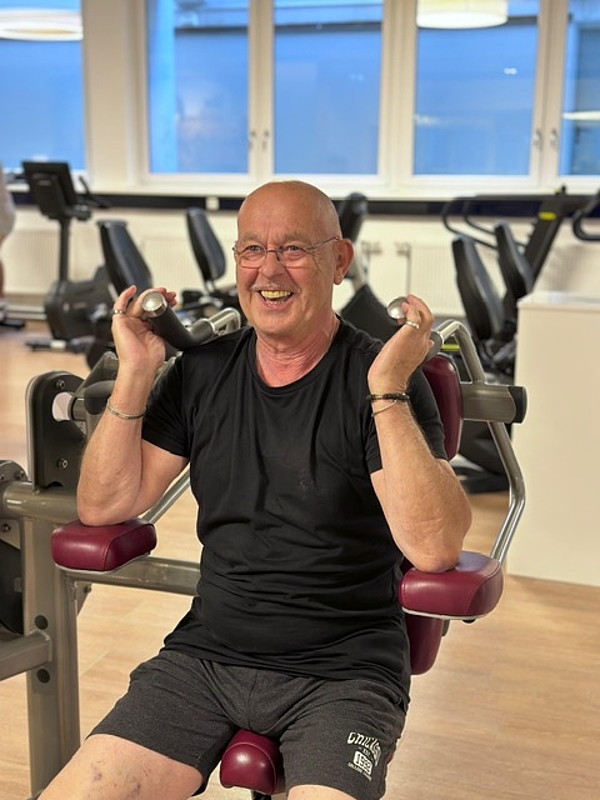 Älterer Mann trainiert lachend an einem Fitnessgerät im Arabella Fitness – Fitnessstudio München-Bogenhausen